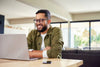 Smiling man using laptop at home, digital tools workspace, creative professional setting